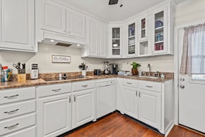 A kitchen with white cabinets, a granite countertop, and a coffee maker. - Tremendous 2-bedroom house with AC in Panama City Beach (Panama City Beach)