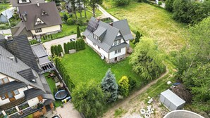 A residential area with a house featuring a sloped roof, a well-maintained lawn, and a small trampoline. - Gronik Mountain Resort 1 Apartment (Kościelisko)