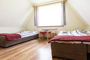 Ein Schlafsaalzimmer mit zwei Betten, einem Holztisch und einem Fenster mit Vorhängen.