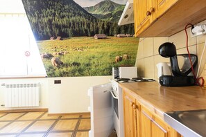 Eine Küche mit großem Fenster, einem Herd, einer Kaffeemaschine und Blick auf eine Berglandschaft.