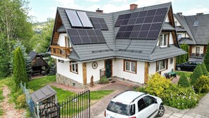 Ett hus med solpaneler på taket, en bil parkerad på uppfarten och en välskött trädgård.
