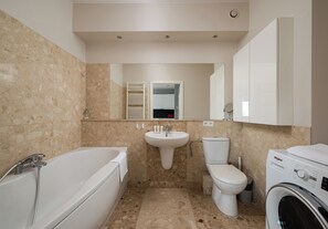 Un baño con bañera, lavamanos, inodoro y lavadora.