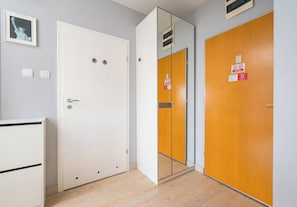 A hotel room with a white door, a mirror, and a wooden door with a sign. - Park Praski Charming Apartment (Warszawa)