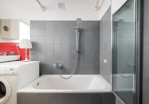 Un baño moderno con bañera, ducha y cabina de ducha con paredes de cristal.