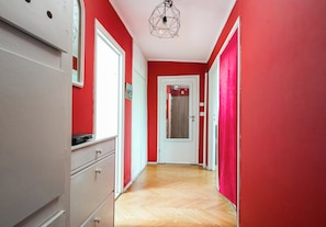A hallway with red walls, a wooden floor, and a white door at the end.