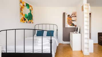 Ein Schlafzimmer mit einem Metallbettgestell, einem weißen Nachttisch, einer grauen Wand und einem Holzboden.