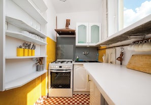 A compact kitchen with white cabinetry, a gas stove, and a checkered floor. - Ogród Saski Homely Apartment (Warszawa)