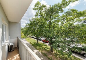 A balcony with a view of a tree-lined street and parked cars. - Kinowa Deluxe | Warsaw Arena Vibes (Warszawa)