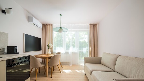 Ett modernt vardagsrum med en soffa, ett matbord, stolar och en tv.
