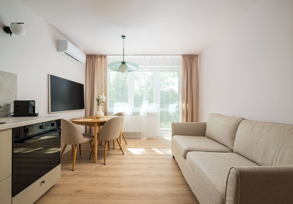 Una sala de estar moderna con un sofá, una mesa de comedor, sillas y un televisor.