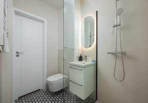 Un baño con inodoro, lavamanos, espejo y ducha.
