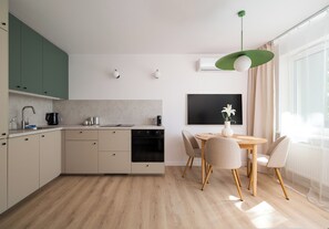 A modern kitchen with a dining area, wooden flooring, and a large window. - Kinowa Deluxe | Warsaw Arena Vibes (Warszawa)