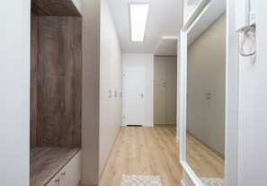 Un couloir avec un banc en bois, une porte blanche et un placard doté de portes coulissantes.