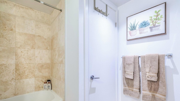 Ein Badezimmer mit einer Badewanne, einer Dusche und einer Tür mit Handtuchhalter.