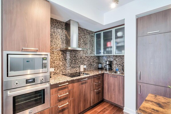 A modern kitchen with built-in appliances, a granite countertop, and wooden cabinets.