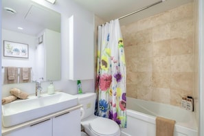 A bathroom with a white sink, mirror, toilet, and bathtub. - Exclusive 1BR Hotel Suite at The Velaire Toronto (Toronto)