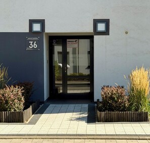 A building entrance with a glass door, a number sign, and a security camera. - Mieszczańska Harmony Apartment (Wrocław)