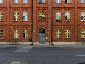 Ein mehrgeschossiges Gebäude aus roten Ziegeln mit vielen Fenstern und einer zentralen Tür.