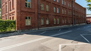 En byggnad med fasad av rött tegel, många fönster och en kullerstensbelagd gata framför.