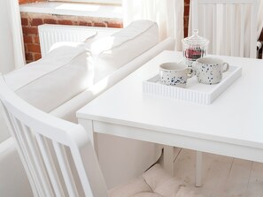 Een witte eettafel met een dienblad waarop twee kopjes en een theepot staan.