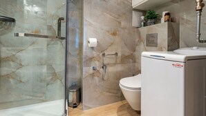 Ein modernes Badezimmer mit einer Duschkabine aus Glas, einer Toilette und einer weißen Waschmaschine.
