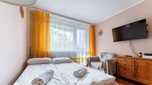 Ein Hotelzimmer mit Bett, Sessel, Fernseher und Holzkommode.