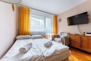 A hotel room with a bed, a chair, a TV, and a wooden dresser. - Sopot Peaceful Retreat Apartment (Sopot)