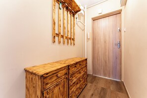 Ein Flur mit einem Holzkoffer, einer Holztür und einem an der Wand befestigten Telefon.