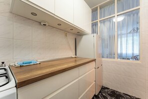 Eine Küche mit Holzarbeitsplatte, weißen Schränken, einem eingebauten Backofen und einem Fenster mit Vorhängen.