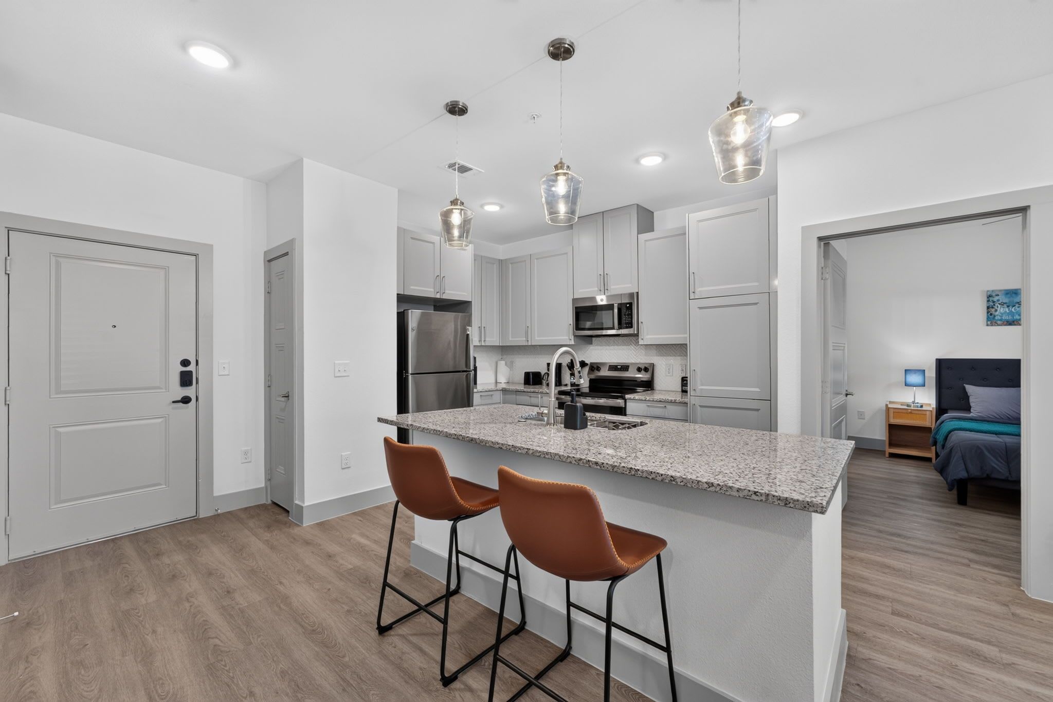 A modern kitchen with a central island, stainless steel appliances, and pendant lighting.