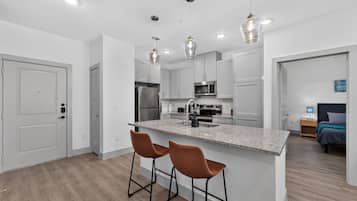 A modern kitchen with a central island, stainless steel appliances, and pendant lighting.