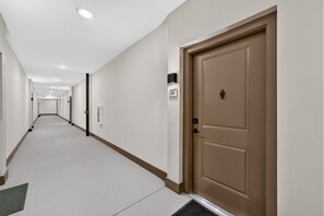 En hotellkorridor med en dubbeldörr, en nummerskylt och en dörrmatta.