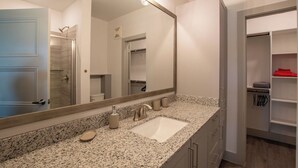Un baño con un espejo grande, un lavamanos y una ducha.