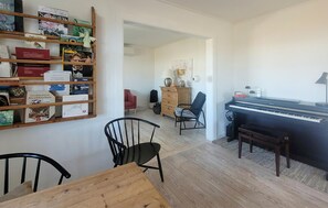 A room with a piano, a wooden table, and a bookshelf with books and decorative items. - Nice home in Tranekær with WiFi (Tranekær)
