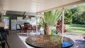 An outdoor patio area with a dining table, chairs, and a kitchen area with cabinets and appliances. - Hop, Skip and a Jump - Entire vacation home on acreage (Landsborough)