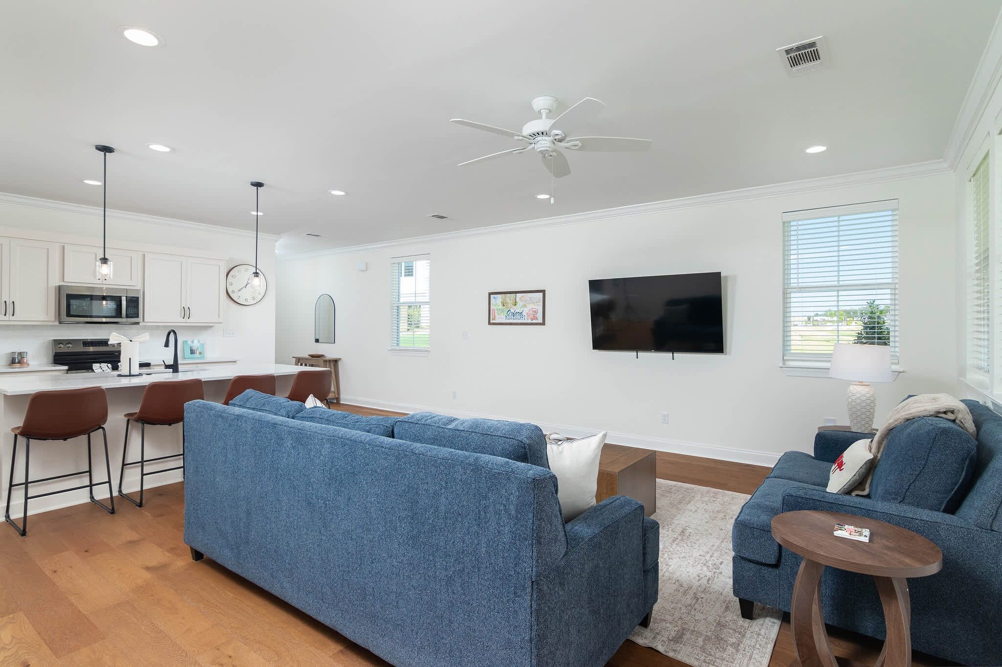 A modern living room with a blue sofa, a coffee table, and a TV mounted on the wall.