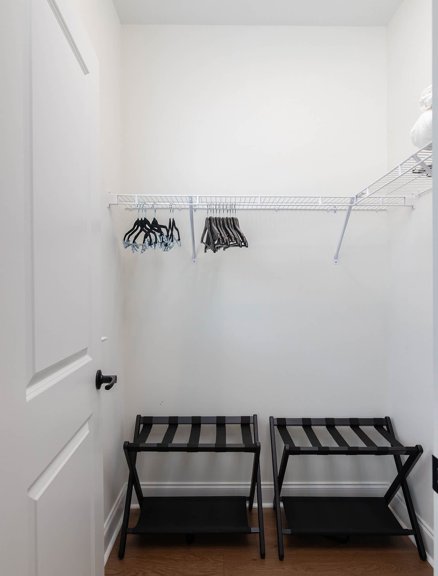 A small, white-walled room with a metal drying rack and two black benches.