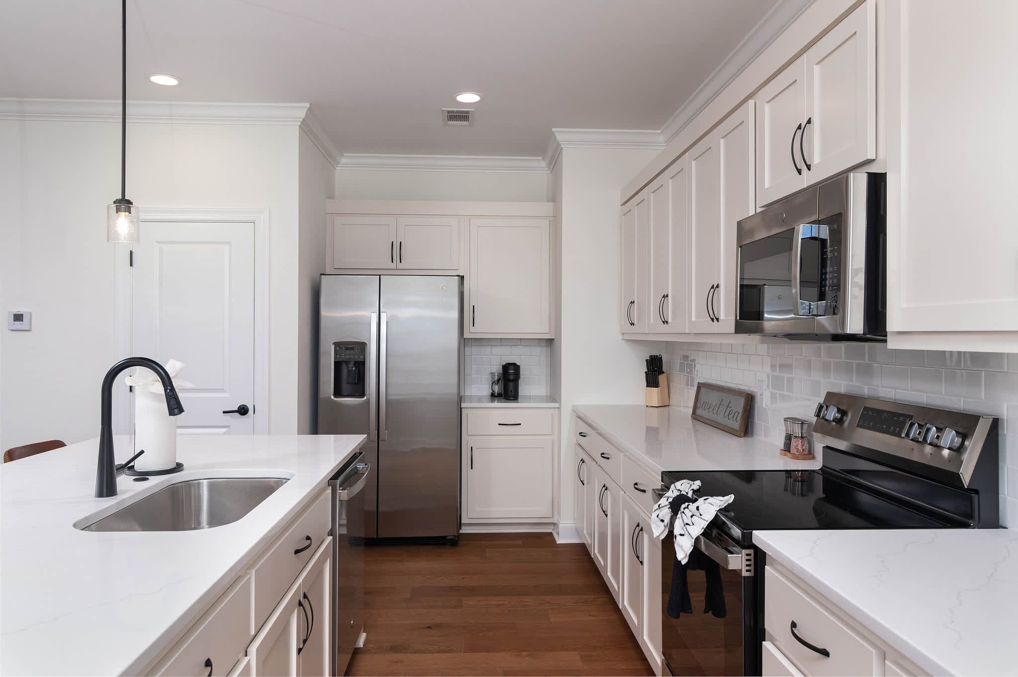 A modern kitchen with white cabinetry, stainless steel appliances, and a marble countertop.