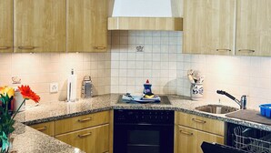 A kitchen with wooden cabinets, a granite countertop, a dishwasher, and a sink. - Haus Alpina (CharmingStay). 2.5-Zimmerwohnung mit zwei Balkonen by Interhome (Mols)