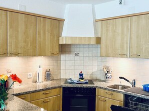 Una cocina con armarios de madera, encimera de granito, lavavajillas y pileta.