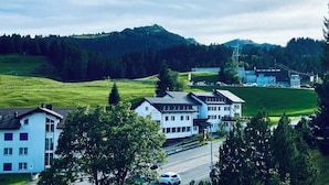 A hotel with a modern design, located in a green valley with a mountain in the background. - Haus Alpina (CharmingStay). 2.5-Zimmerwohnung mit zwei Balkonen by Interhome (Mols)