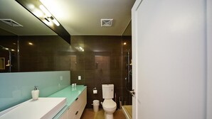 Ein modernes Badezimmer mit Waschbecken, Toilette und einer Duschkabine aus Glas.