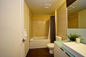 A bathroom with a bathtub, toilet, and a sink with a mirror.