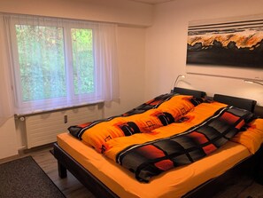Une chambre à coucher avec un lit, une fenêtre avec des rideaux, un radiateur et un tableau accroché au mur.