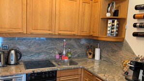 A kitchen with wooden cabinets, a stainless steel sink, a stove, and a coffee machine.