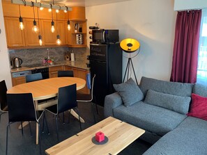 A compact living space with a kitchenette, a dining area, a sofa, and a floor lamp.