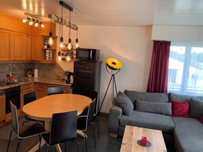 Un espace de vie compact comprenant une cuisine, un coin repas et un coin salon.