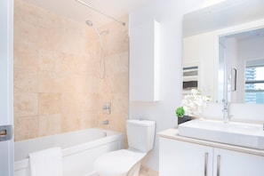 A modern bathroom with a bathtub, toilet, and sink. - City 1BR Hotel Suite with 3 Beds | Sleeps 6 (Toronto)
