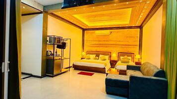 A modern hotel room with a bed, sofa, and a TV mounted on the wall.