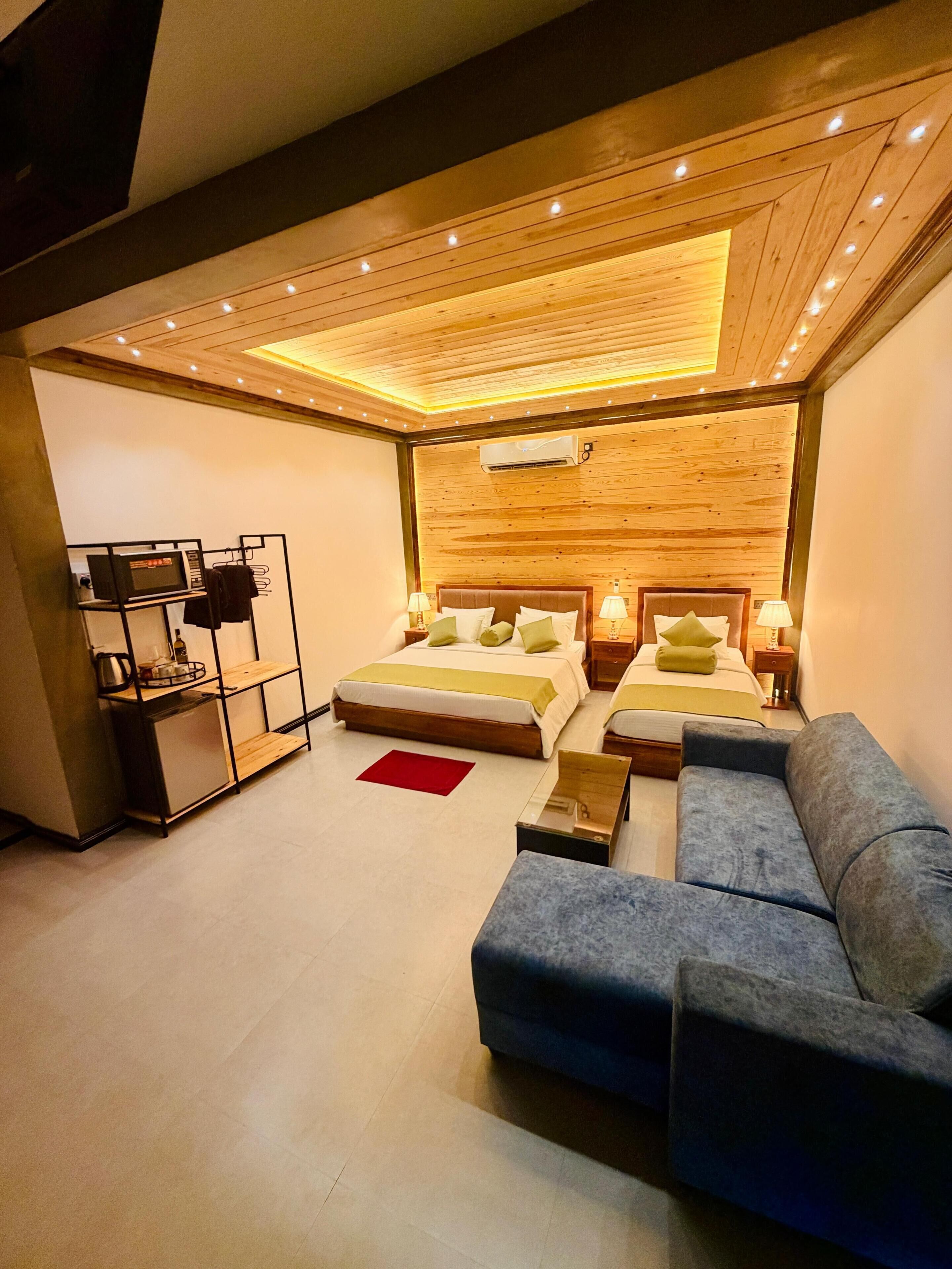 Un dormitorio moderno con dos camas, un sofá, una mesita y un mueble para televisor.